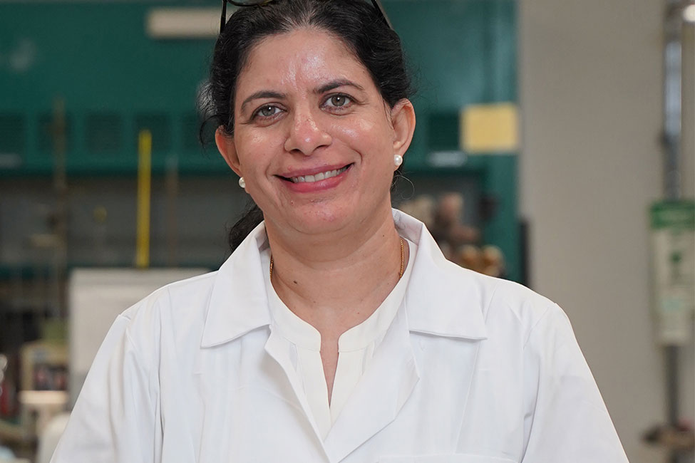 Photo of Shailaja 所有ani, Ph.D., standing in her lab wearing a white lab coat.