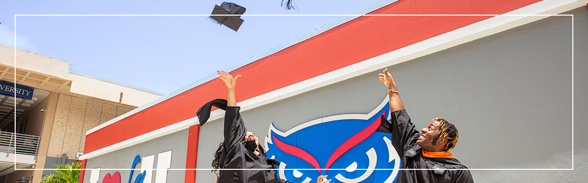 Two students throwing their graduation caps in the air in celebration