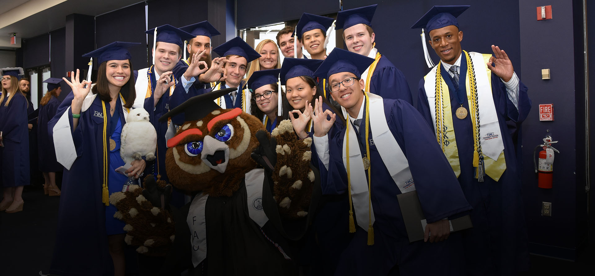 FAU Mascot Owlsley standing with Honors College graduates in regalia