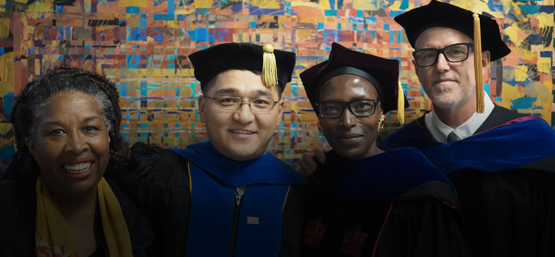 Three Honors College professors in regalia smiling