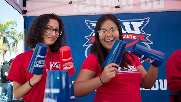 Two students in FAU gear hold FAU cups 