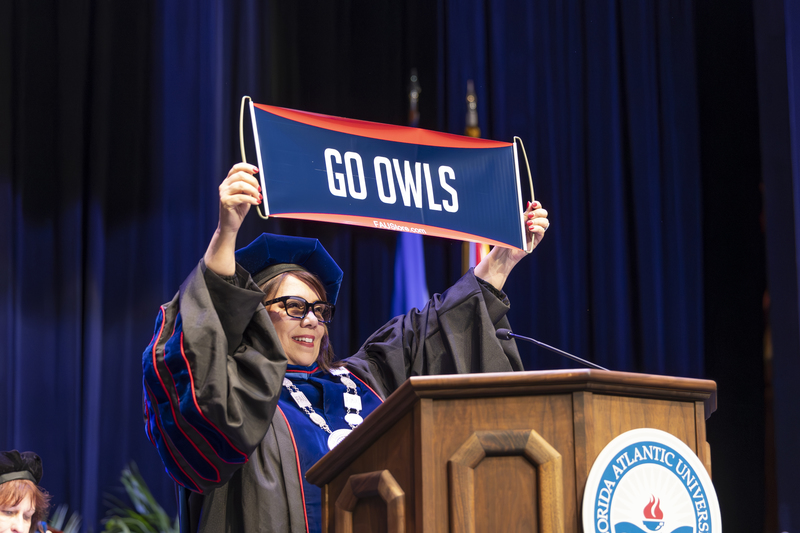 Stacy Volnick holding up "GO OWLS" banner