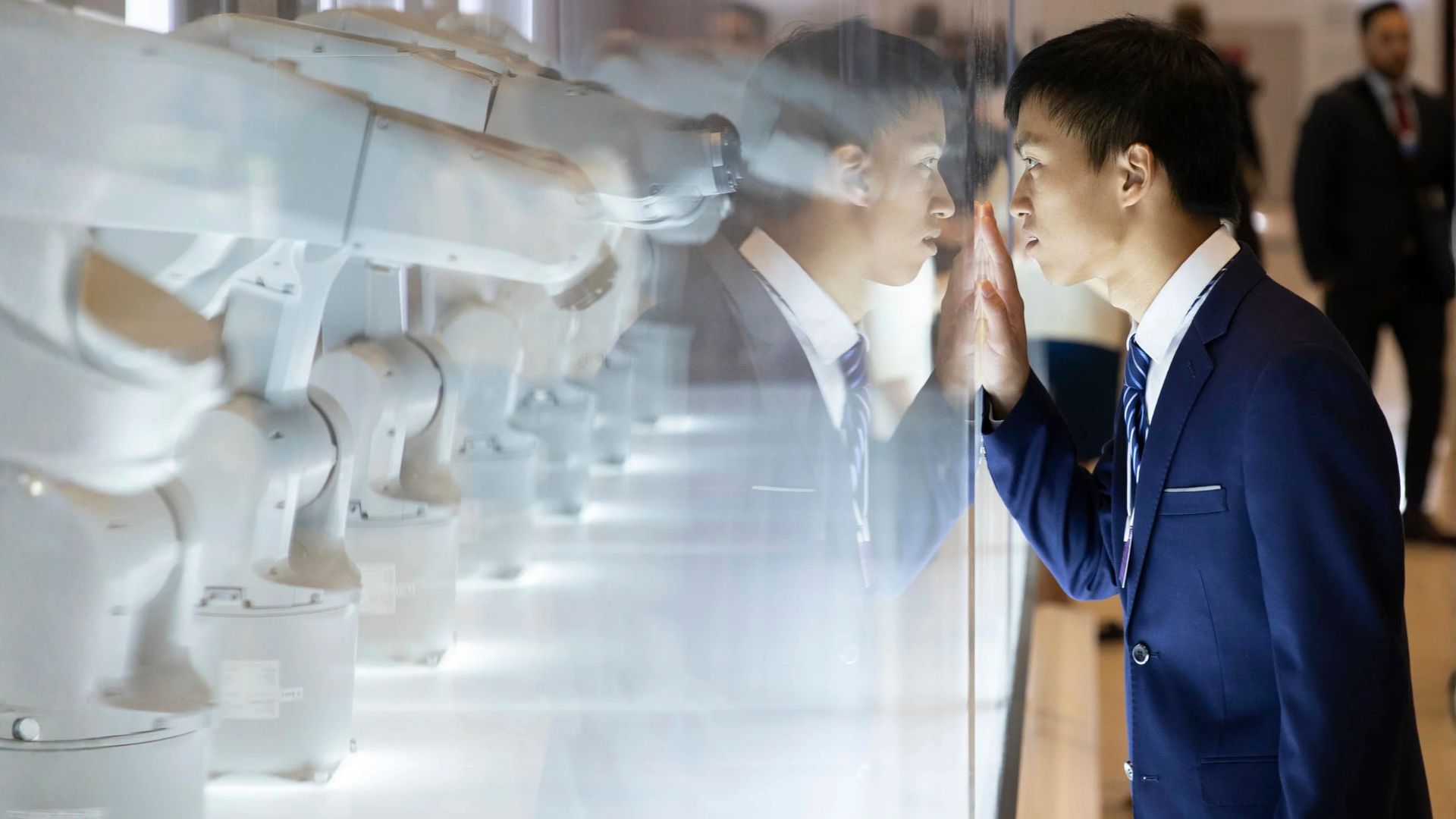 Man looking through glass at robotic arms