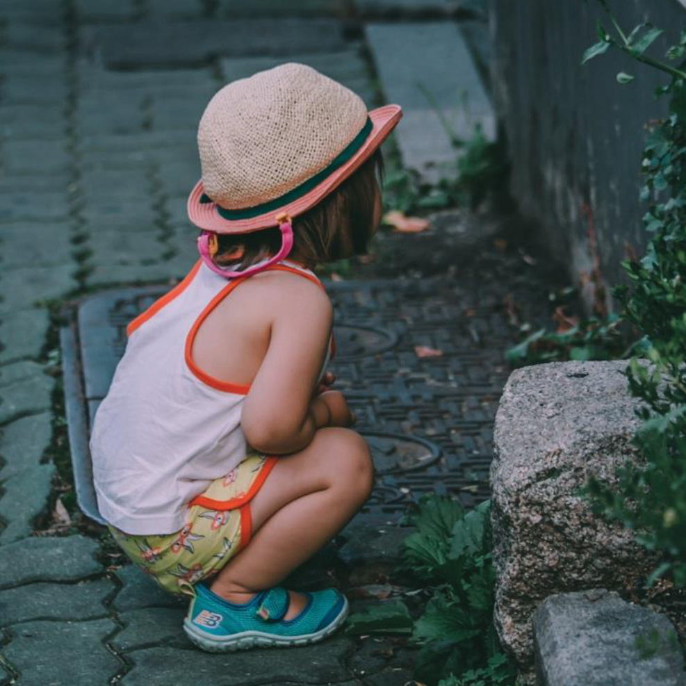 girl earing a hat looks at ivy wall