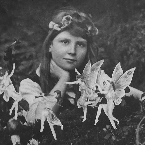 Black-and-white photograph of a young girl resting her chin on her hand, surrounded by small winged fairy figures