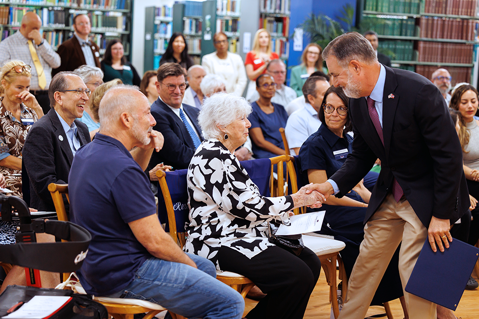 FAU President Adam Hasner shakes hands with FAU benefactor Charna Larkin before they cut the ribbon to open the Alan B. and Charna Larkin American Presidential Study in the S.E. Wimberly Library at the Boca Raton campus. Seated right is Jonathon Larkin, son of Charna Larkin; left is FAU First Lady Jillian Hasner.