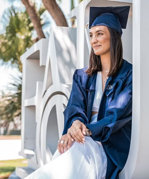 Student Graduate sitting in FAU sign