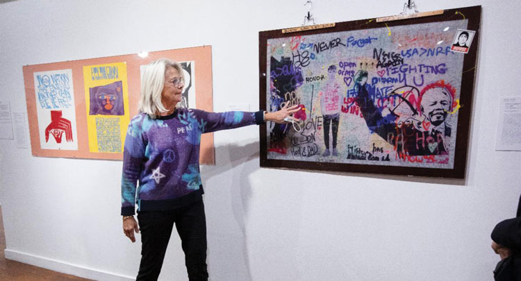 Barb Schmidt with the painting, "I Wish I Was Here" by Manuel Oliver (2019)