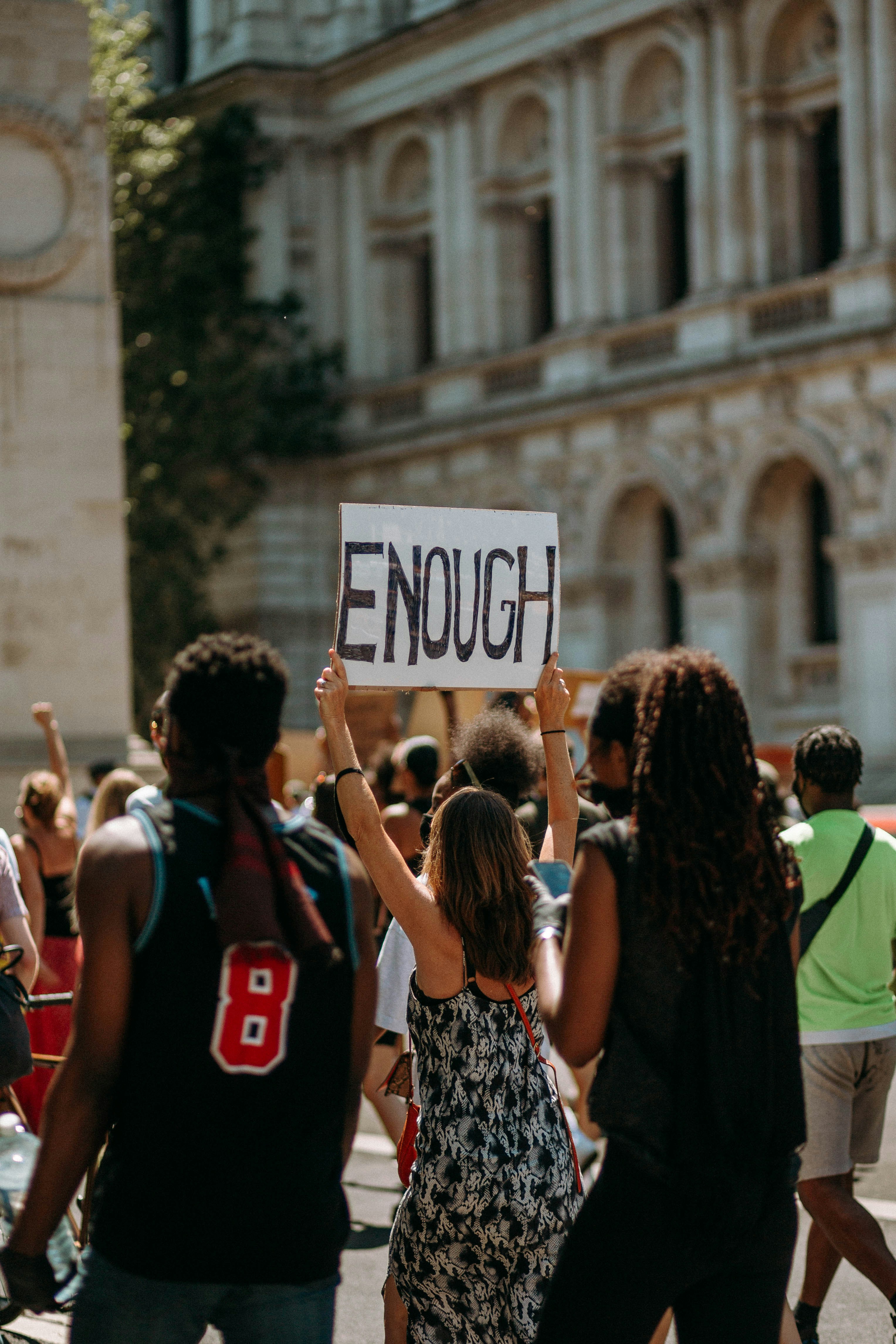 Women holding up a sign with the word "ENOUGH" during a march of protest.