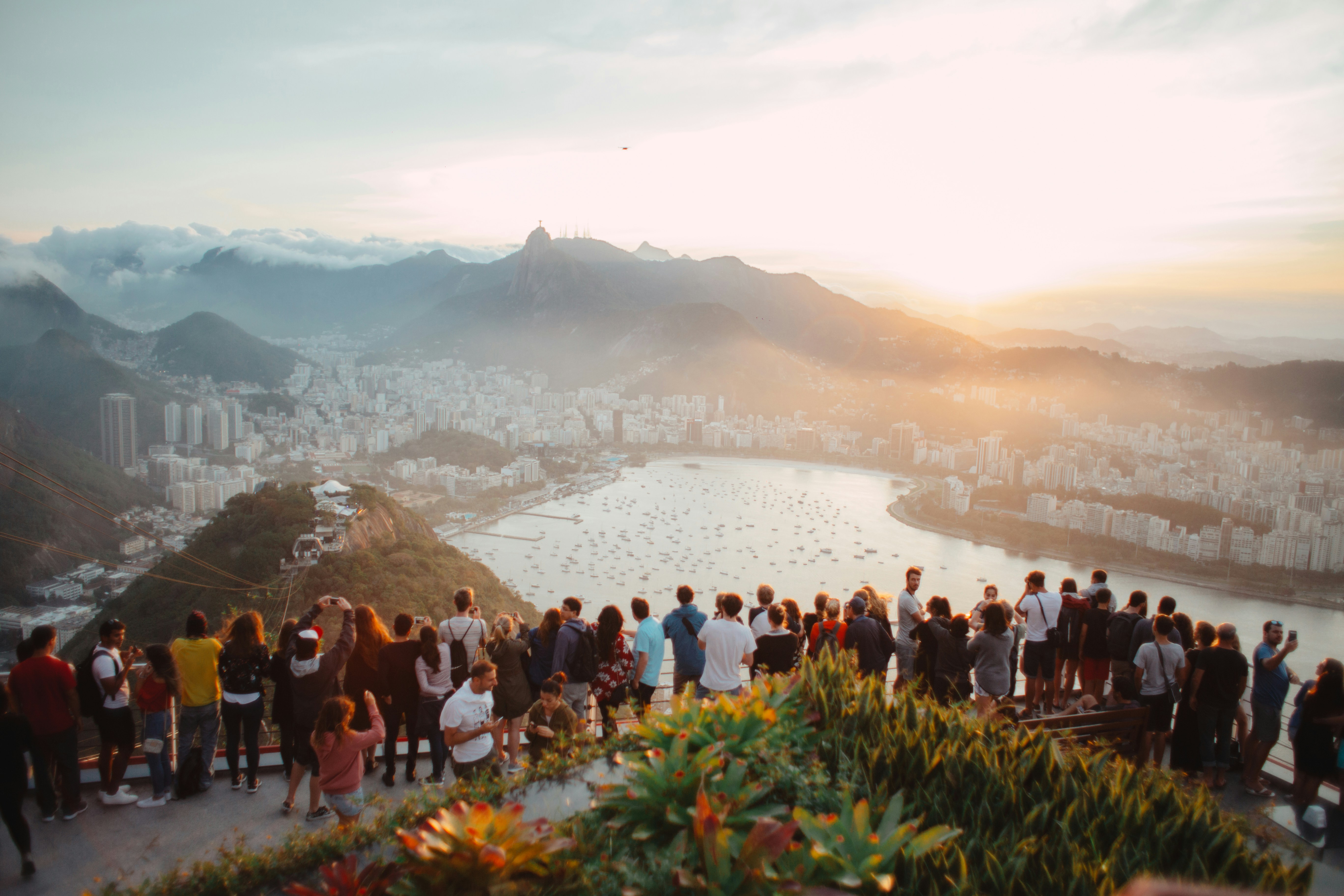 Tourists overlooking a city with buildings a lake and mountains.