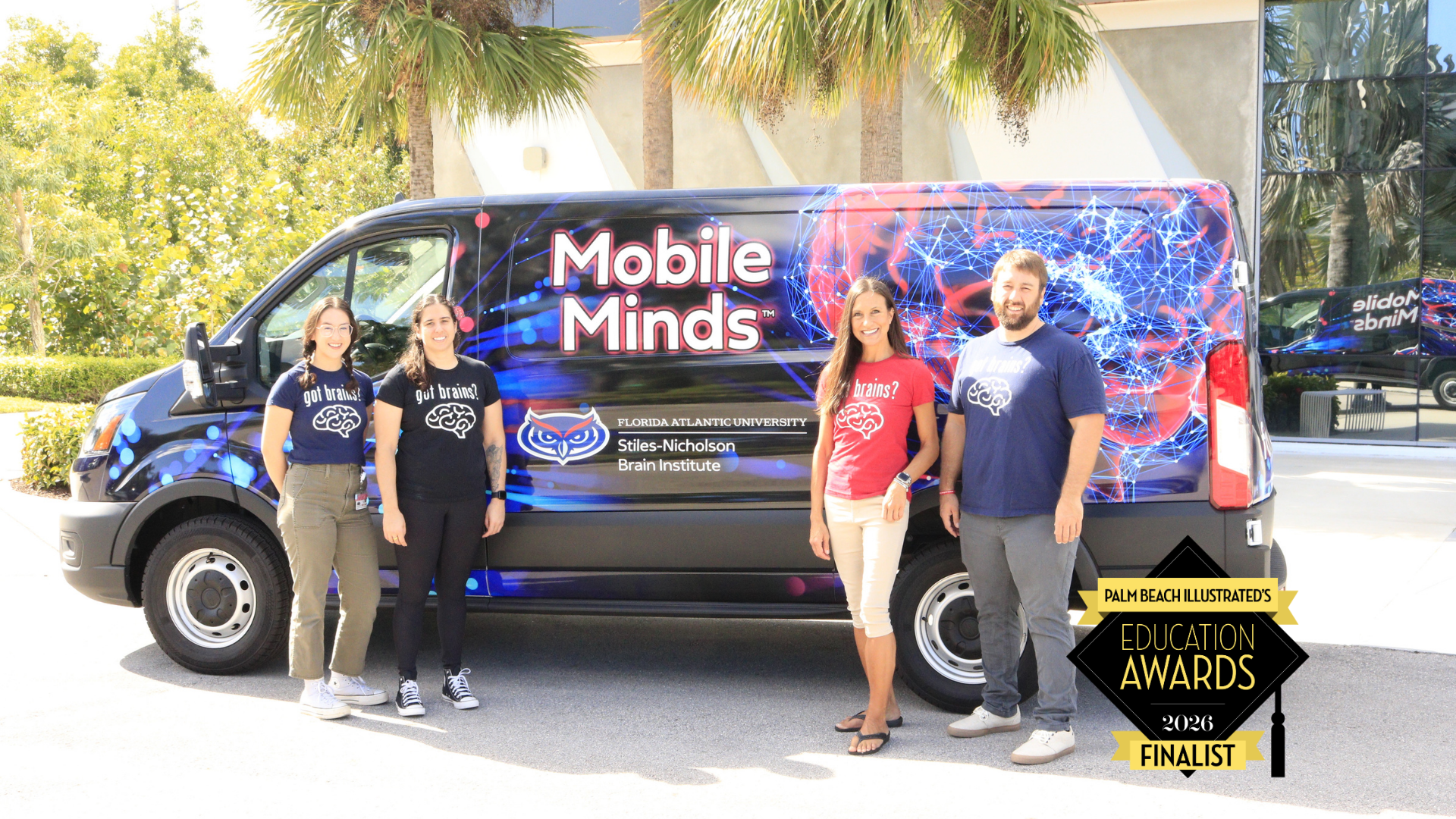  center background is a van with red and blue accents including a brain illustration and the words 'mobile minds' in white text. in the foreground are 3 women and a man all wearing tshirts that say 'got brains?" 