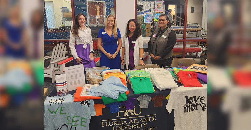 Group smiling for a photo standing at a table 