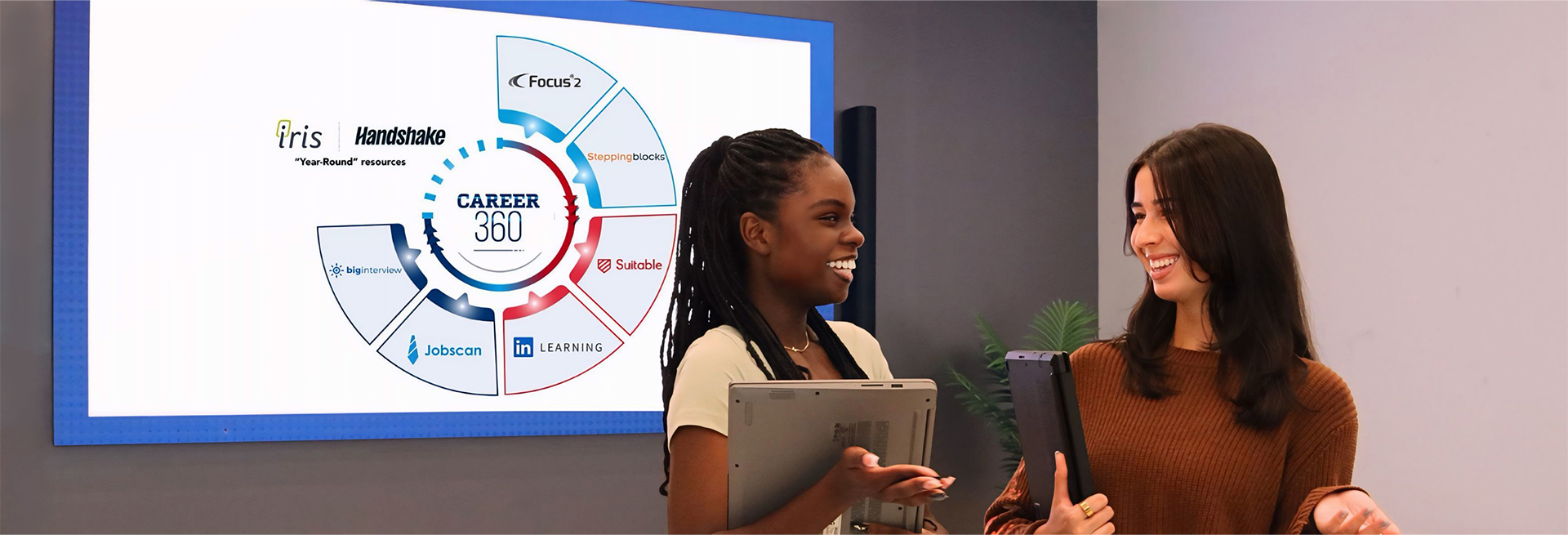 Two young ladies smiling in from of the Career 360 sign.