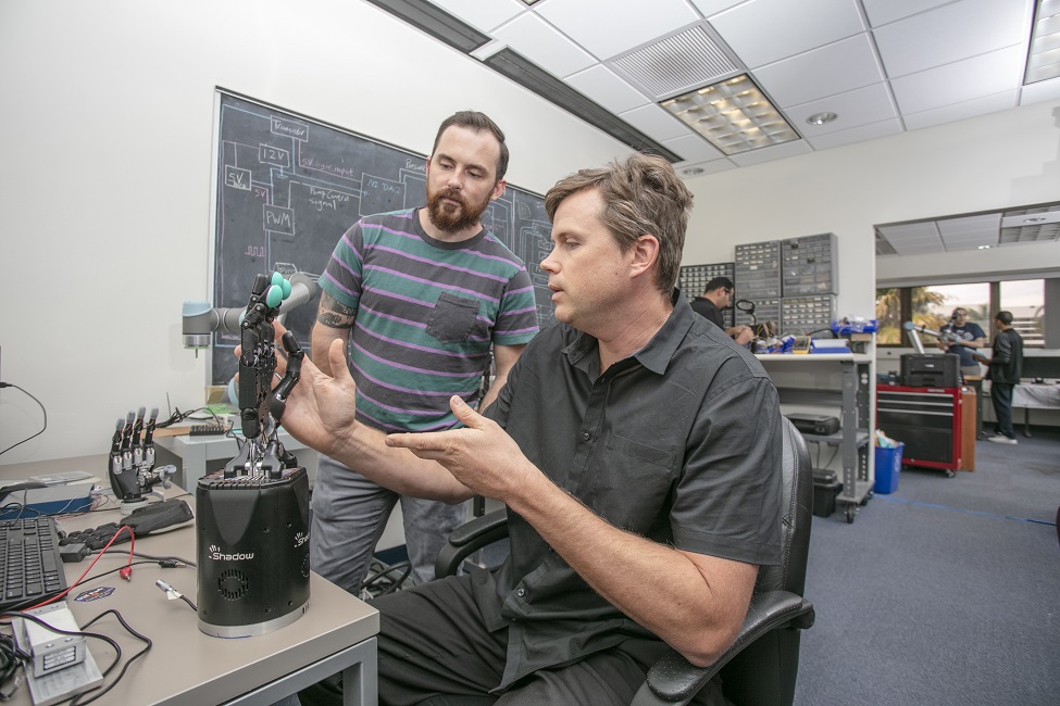 Erik Engeberg, Ph.D., (seated) senior author, pictured with the dexterous artificial hand used for the study. (Photo by Alex Dolce)
