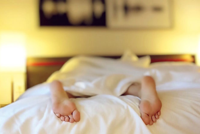 a person in bed with their feet sticking out from under the blanket