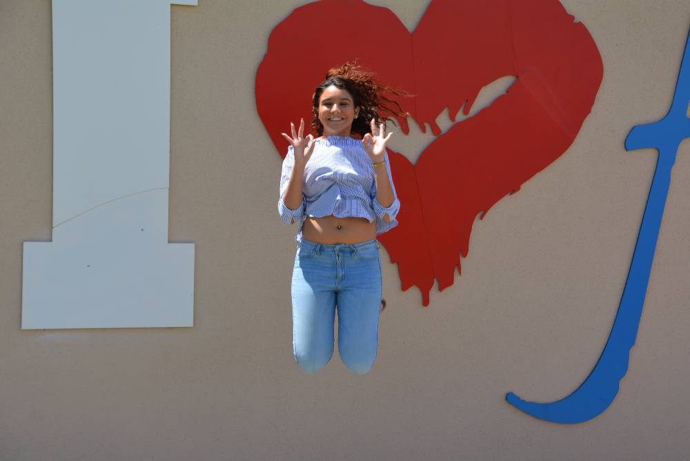 girl jumping in front of i love FAU sign