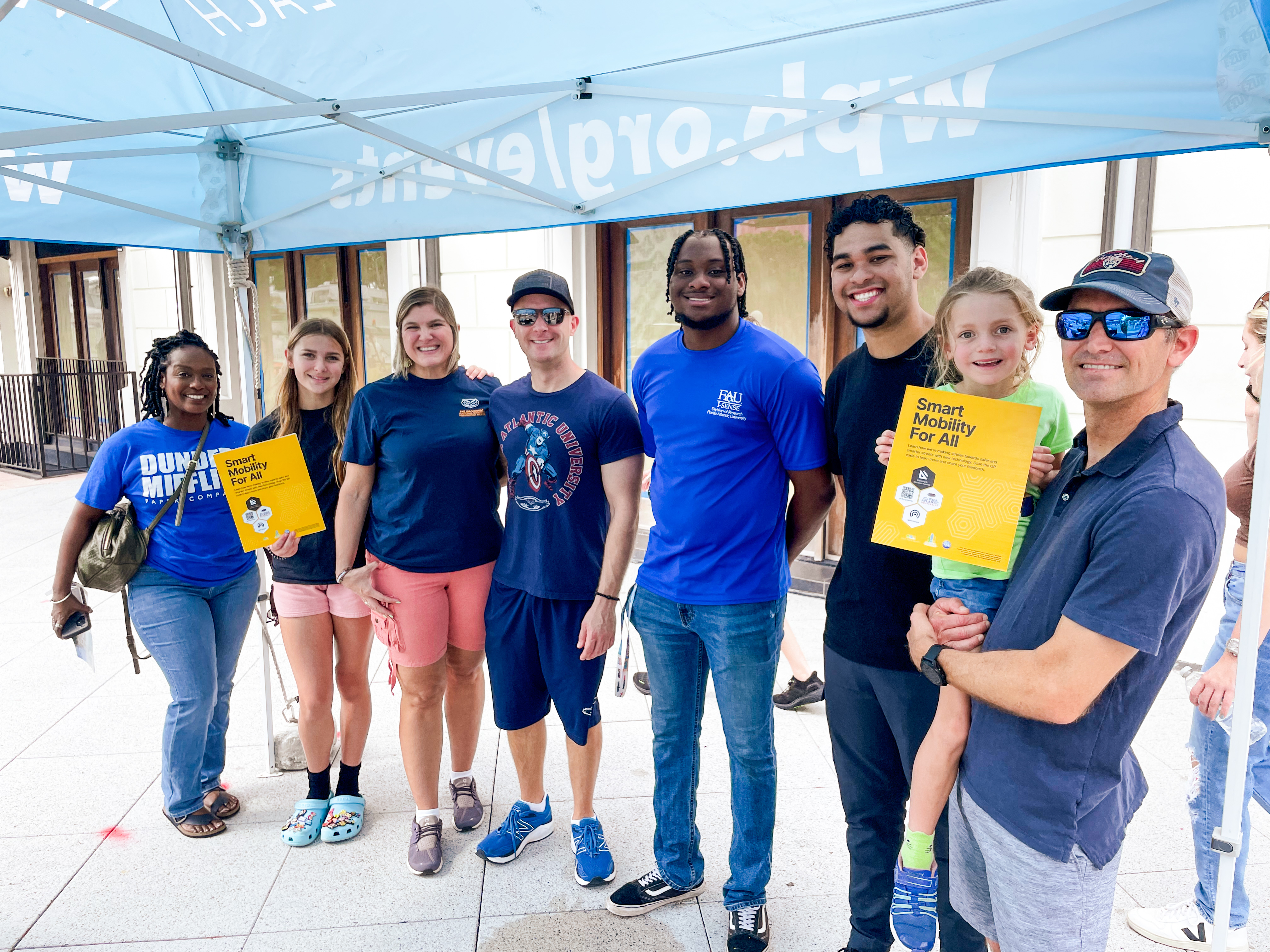 group of people in blue tshirts holding yellow signs standing in front of windows