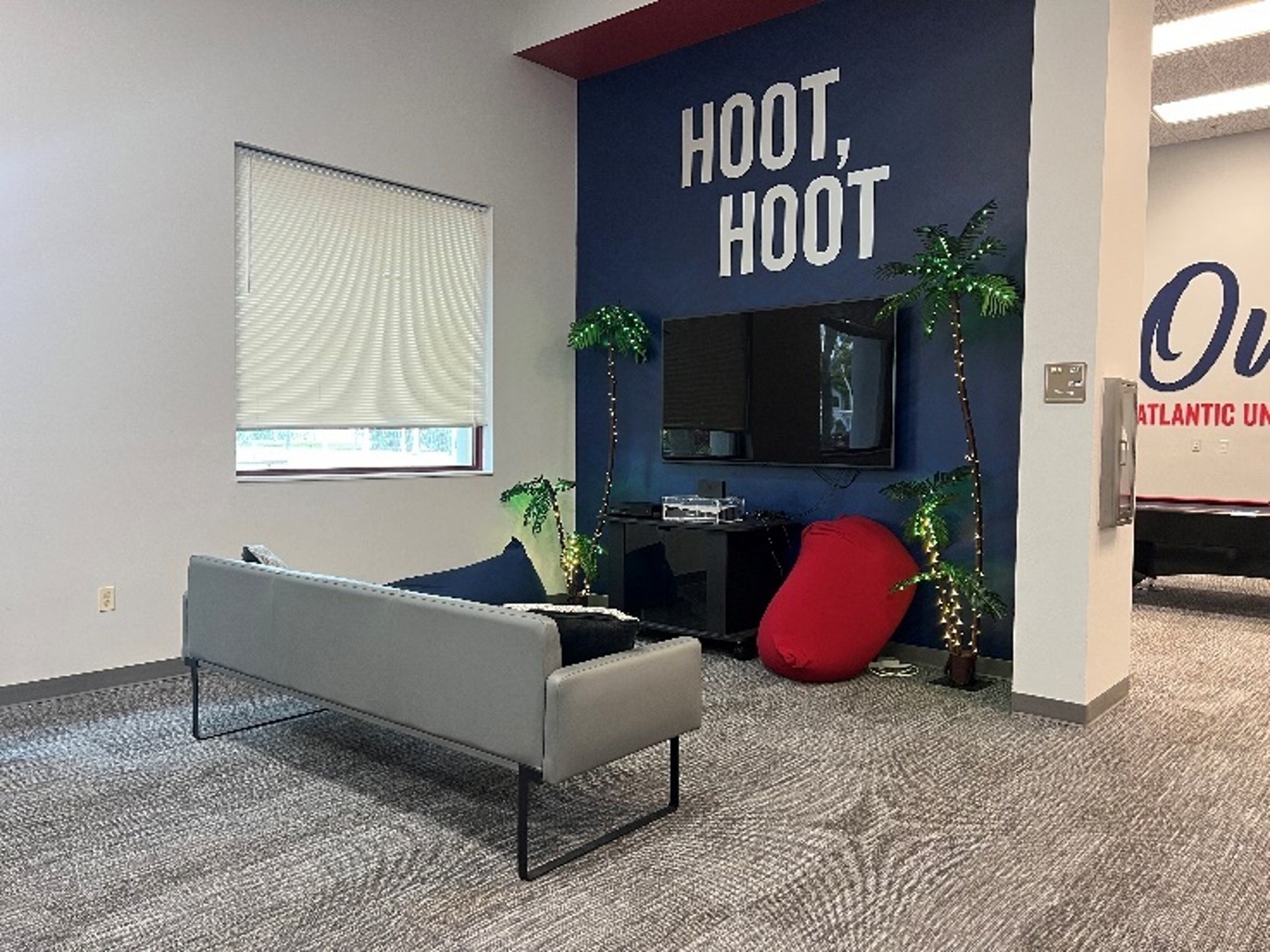 view acing wall with two windows, sofa, bean-bag chairs, wall with words Hoot, Hoot