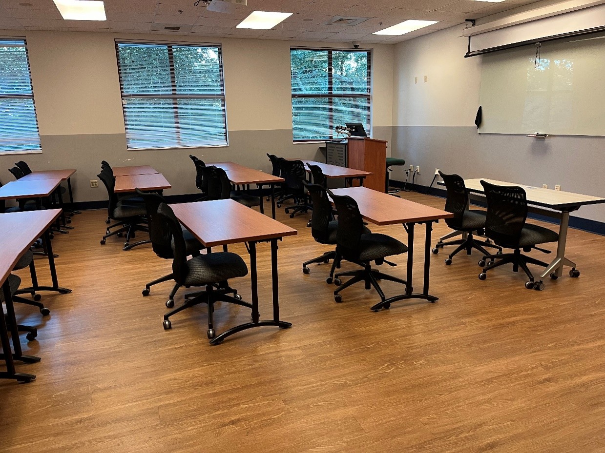 side view of classroom with brown tables and black chairs, pull-down screen