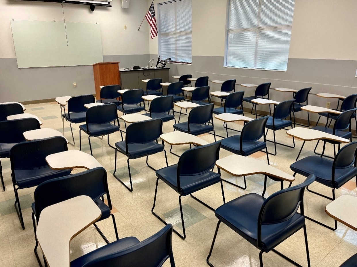 back view of classroom with flip-top desks, windows, projector