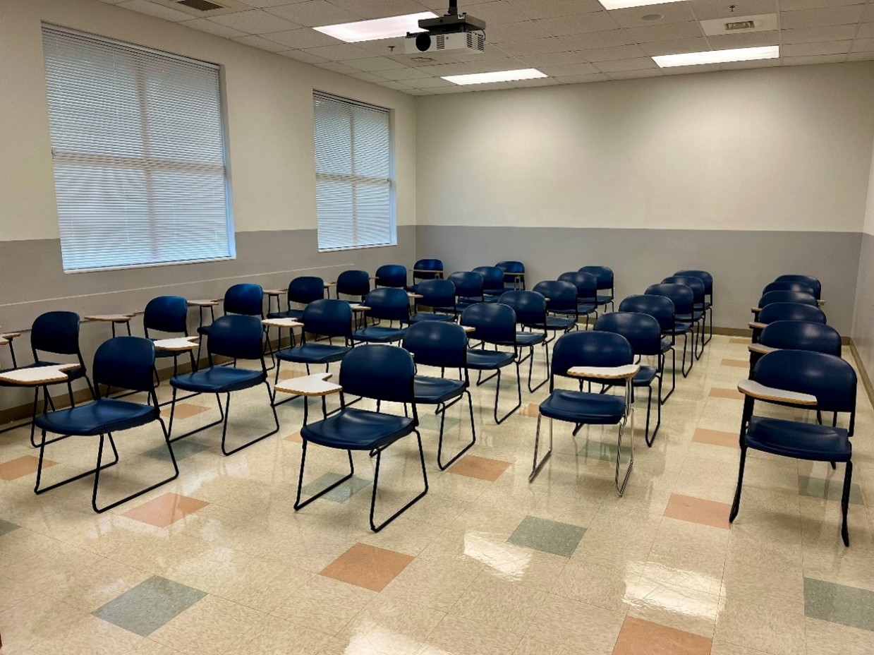 front view of classroom with flip-top desks, windows, projector