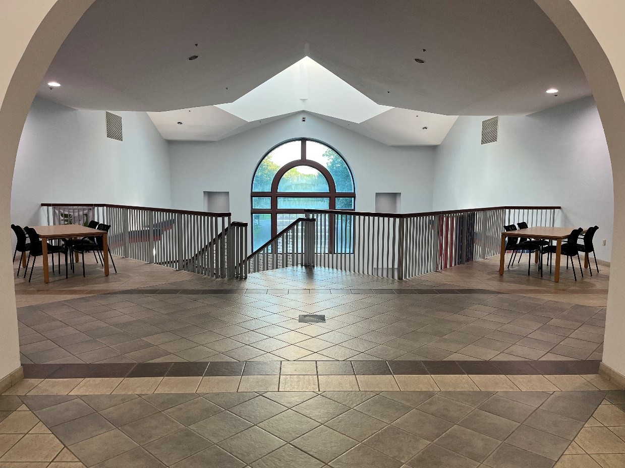 view facing stairs with railings, large window, tables and chairs