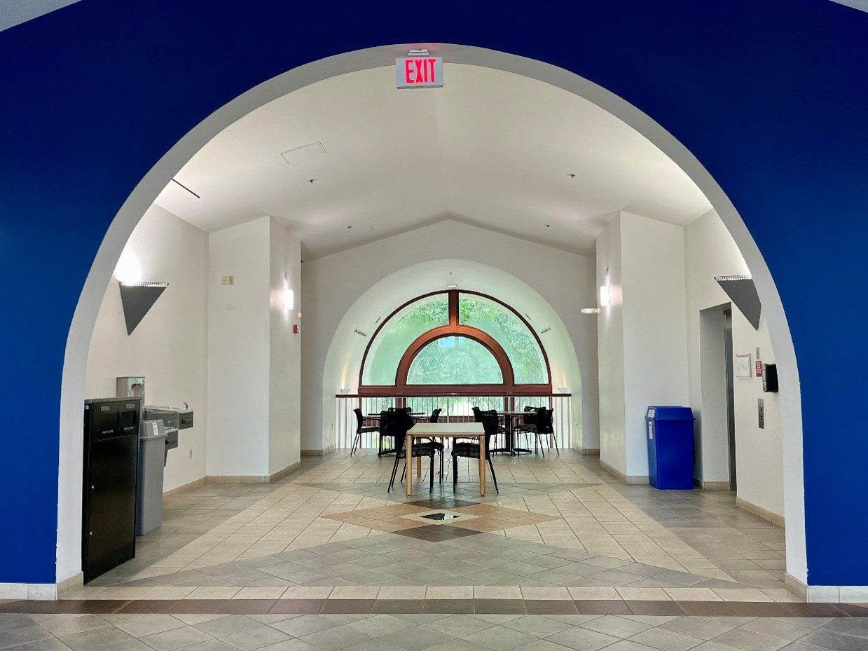 view into large hallway with arched entryway, window, chairs, tables