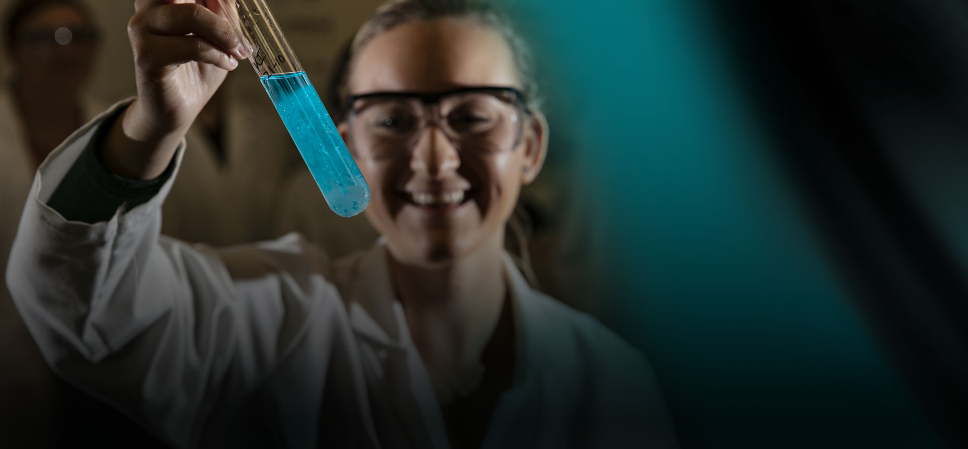 Student holding a test tube on a black and green abstract background
