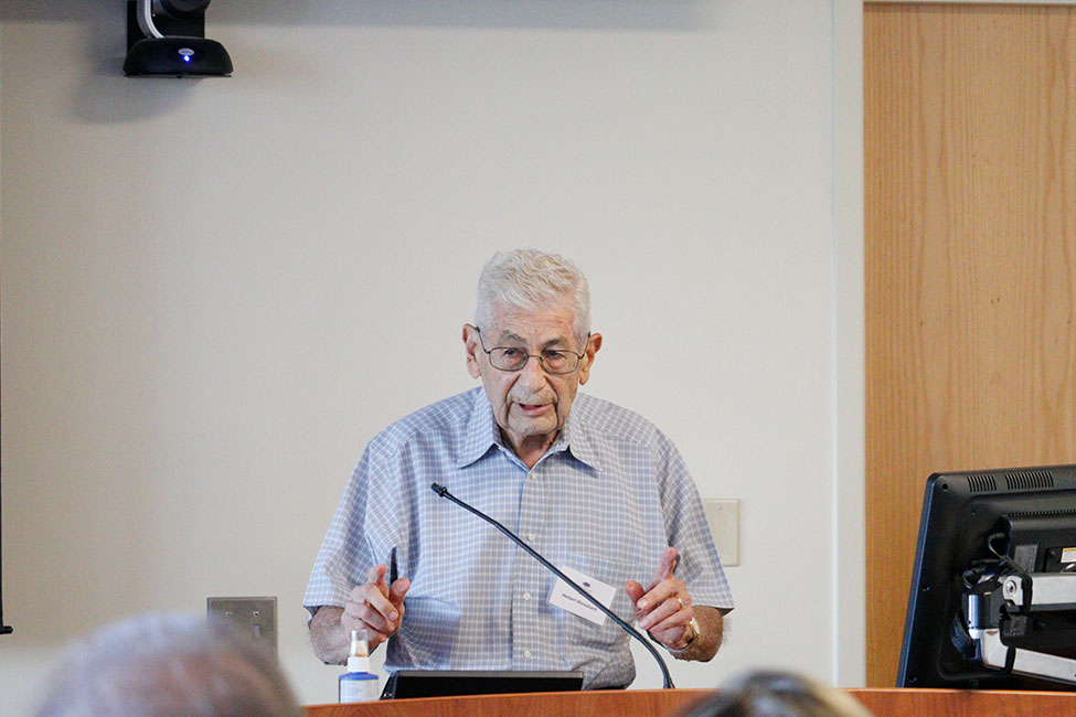 A man stands speaking behind a lectern. 