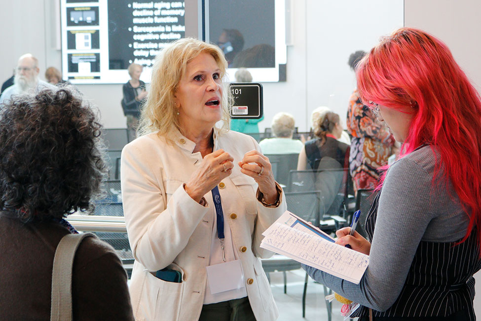 A person speaks to another person who is taking notes while a third person listens.