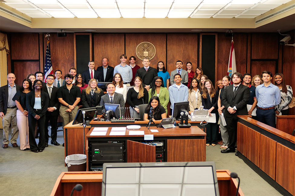 Courtroom group photo with students, judge, and legal professionals.
