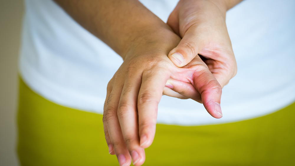 Person holding their hand near the thumb and wrist, illustrating arthritis pain