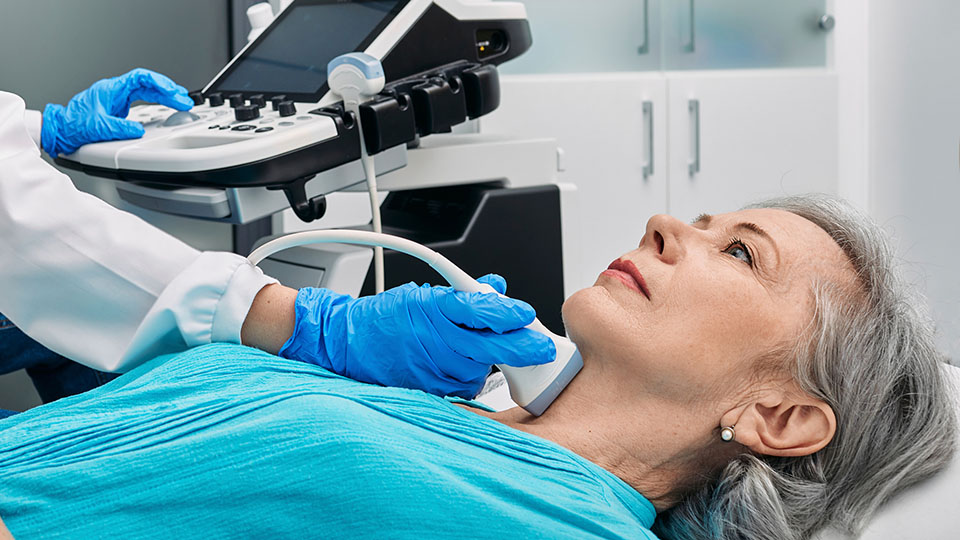 Doctor performing thyroid examination on woman