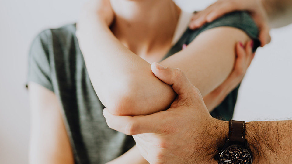 Doctor testing arm and elbow joint of patient