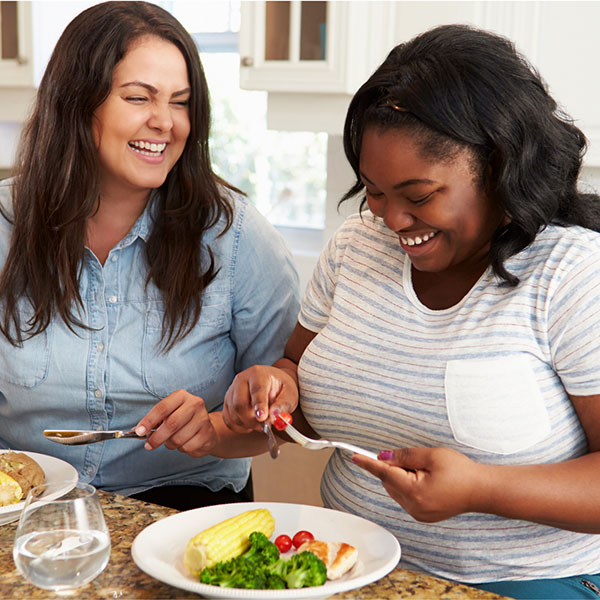 Two women eating a healthy meal together in the kitchen