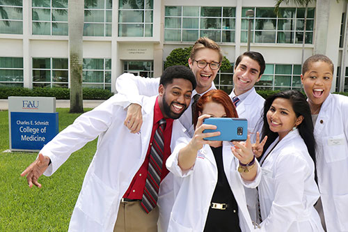 FAU medical students taking group selfie in front of the Schmidt College of Medicine building in Boca Raton, FL