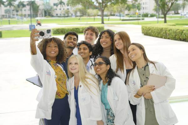 FAU Medical Students taking group selfie in front of Schmidt College of Medicine building