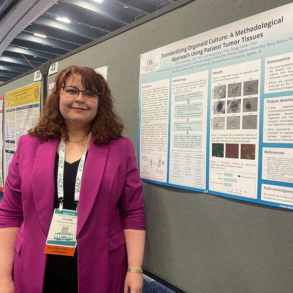 Resident standing in front of poster presentation at national research conference