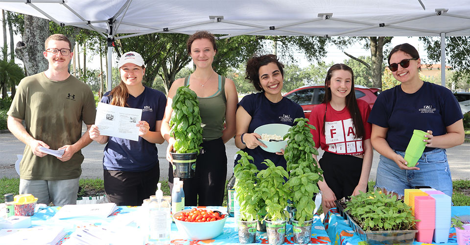 Project Grow medical students showing tomatoes, salads, and beans grown in the garden under a tent