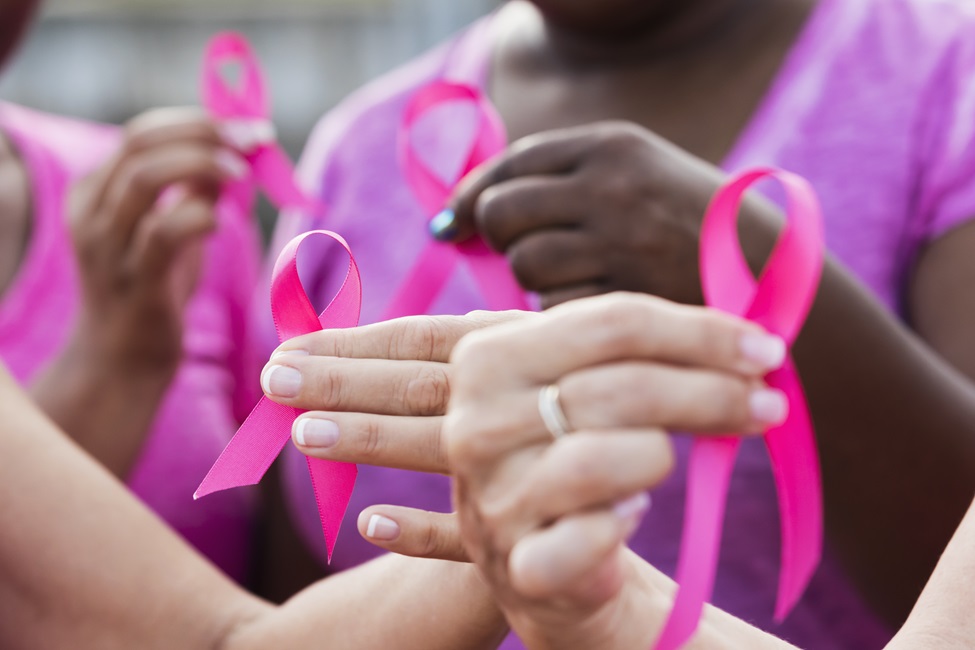 Women holding up pink ribbons in their hands