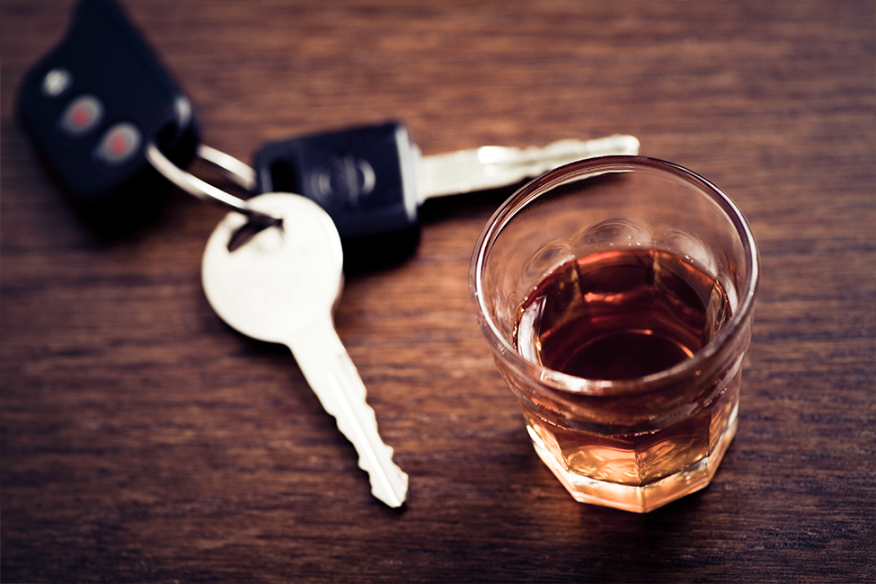 A glass of alcohol next to a set of car keys