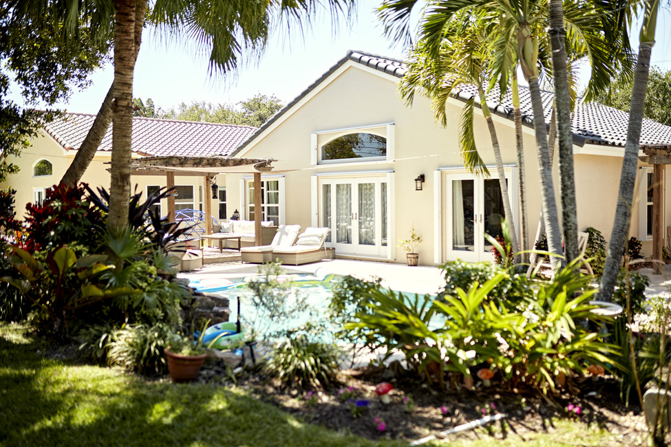 The backyard of a white house with a pool.