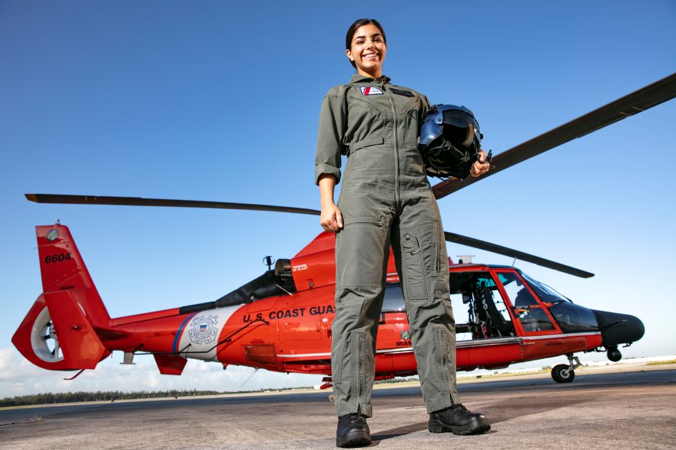 A member of the FAU military poses next to a helicopter