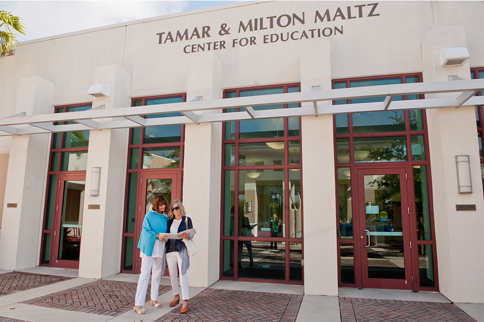 Two women reading outside of Osher LLI Building 