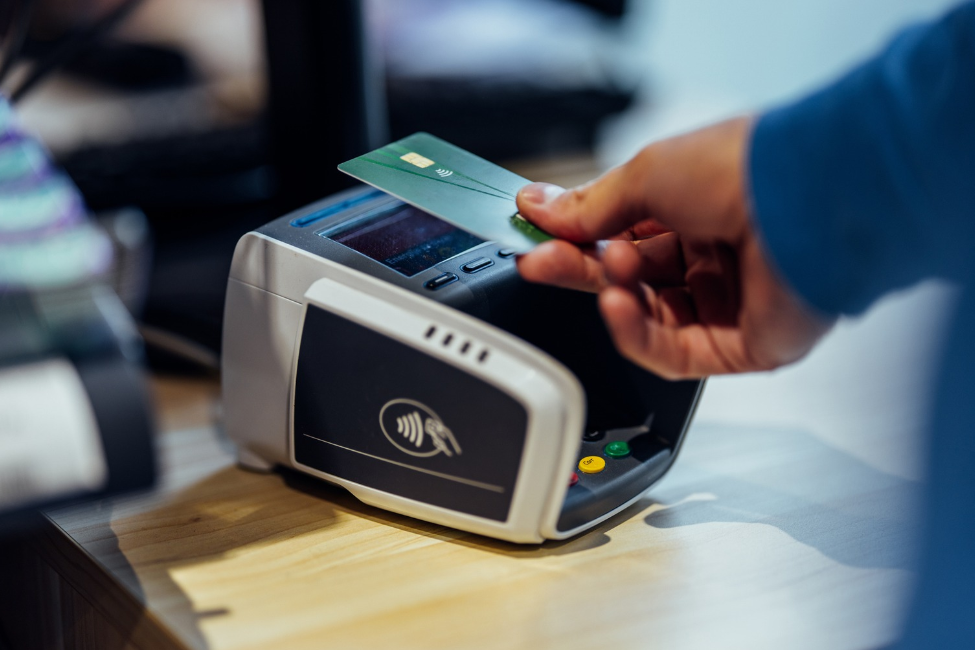 A hand presses a green credit card to a register 