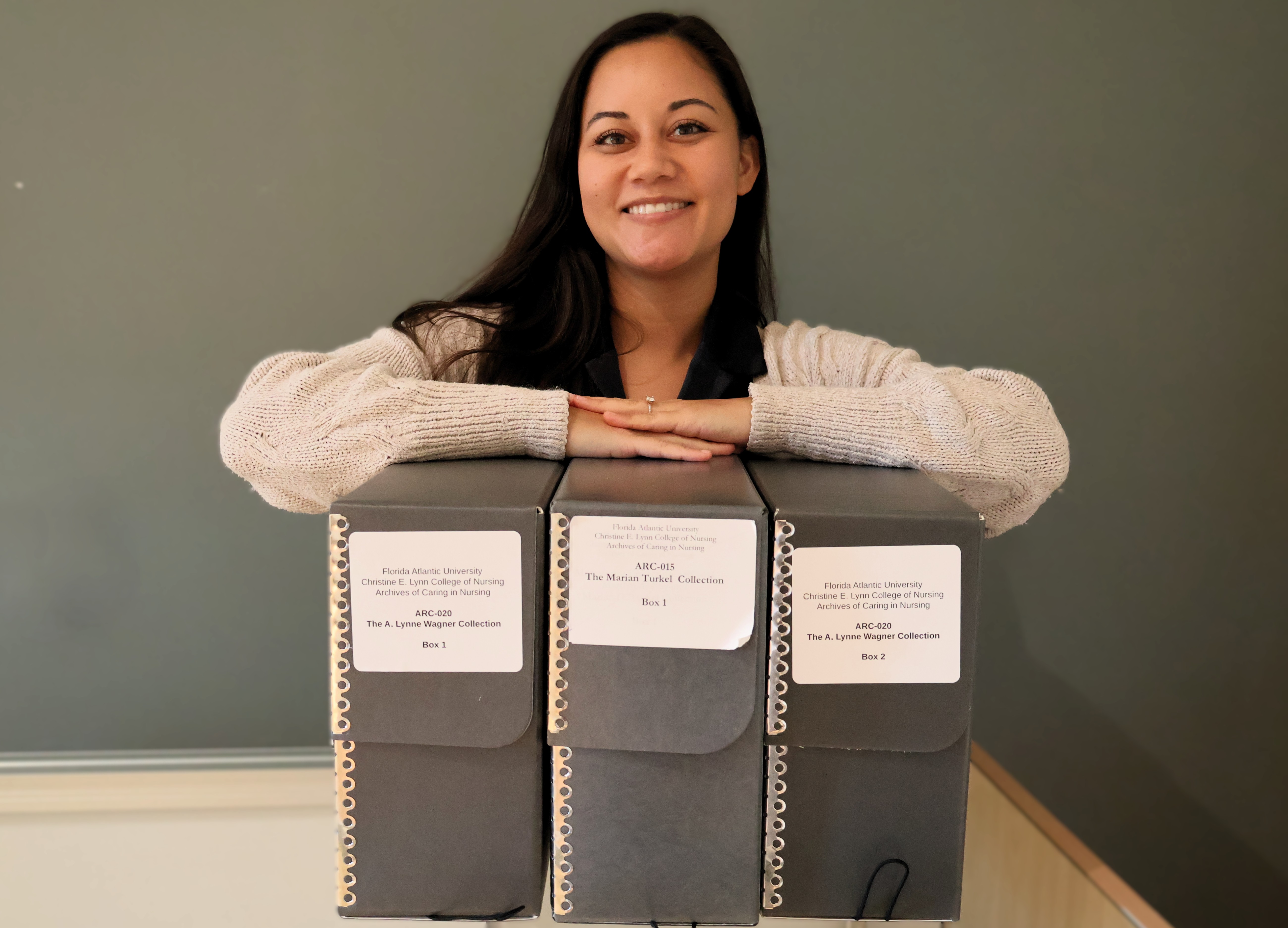 Cassandra Bower with the three large folders on the new materials at the Archives of Caring