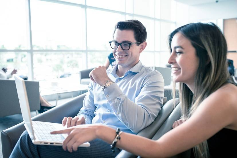 Two FAU students sitting together at a table and reviewing a website.