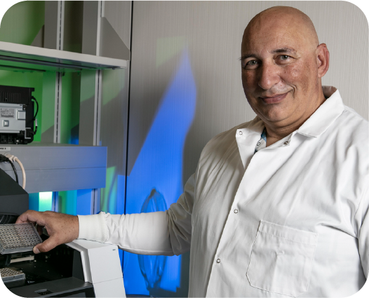Massimo Caputi, Ph.D., standing in front of a COVID-19 testing protocol machine.