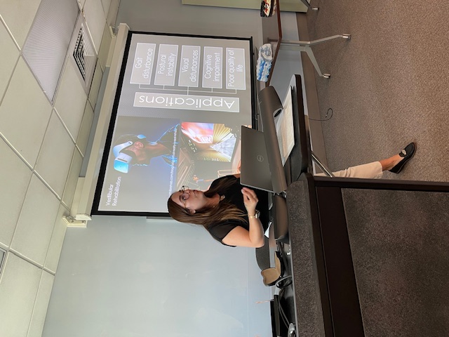 A presenter stands in front of a screen displaying a thesis and dissertation workshop slide.