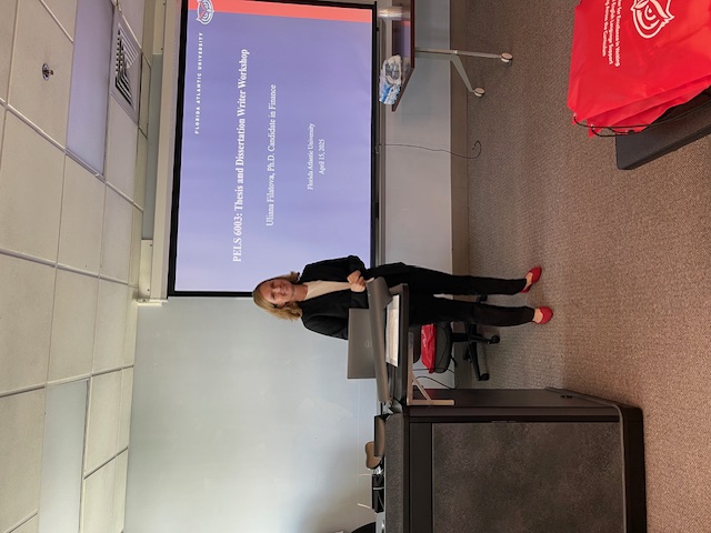A presenter speaks at a podium with a slide about climate change projected on the screen behind them.